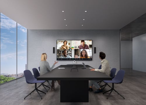 A meeting room with two people having a virtual call with four other people.