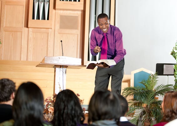 A man holding the bible and a mic in front of a crowd