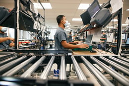 Man looking at a computer next to a warehouse.